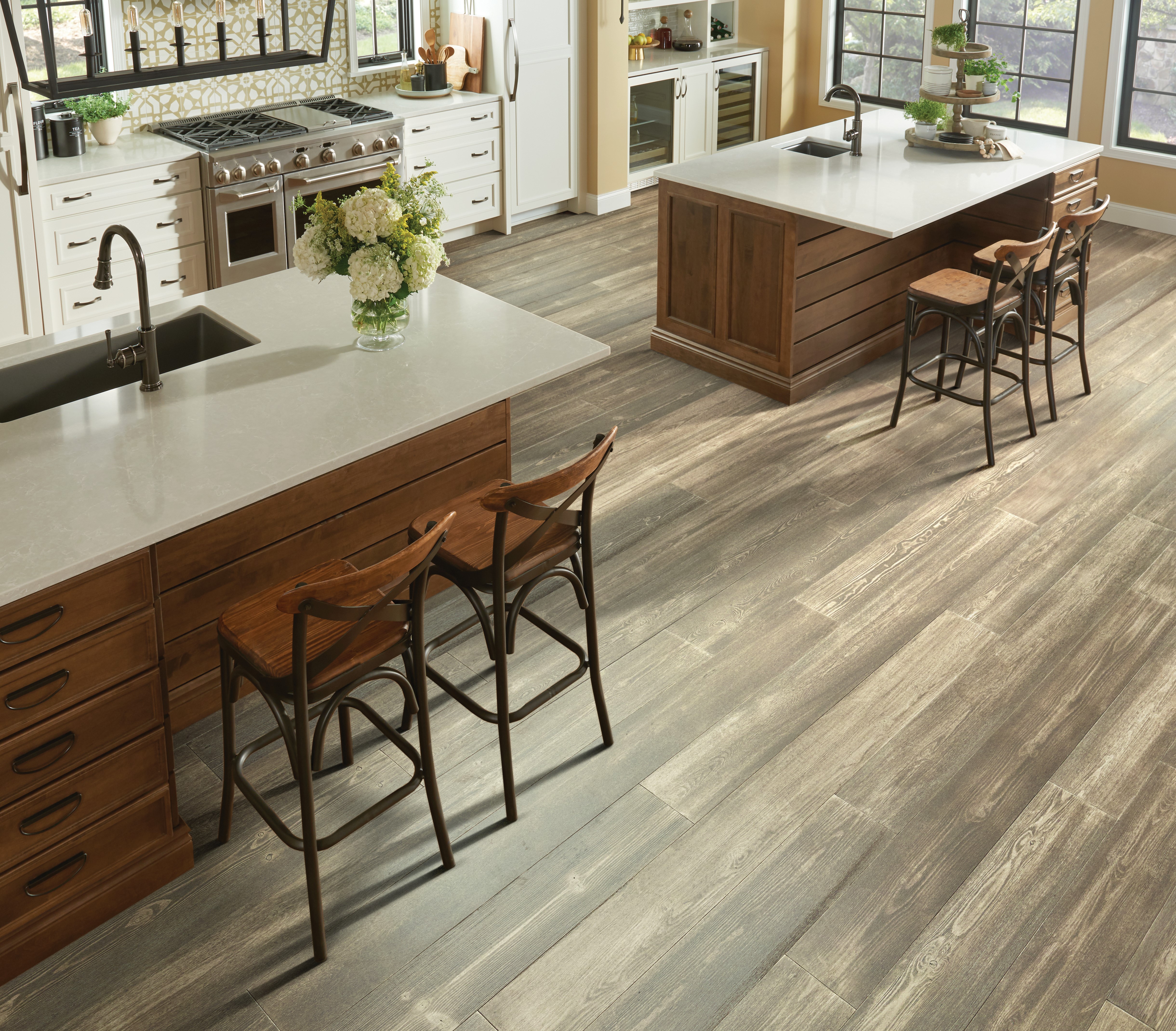 Kitchen scene featuring warm tones, two granite islands, stove, hardwood floors.